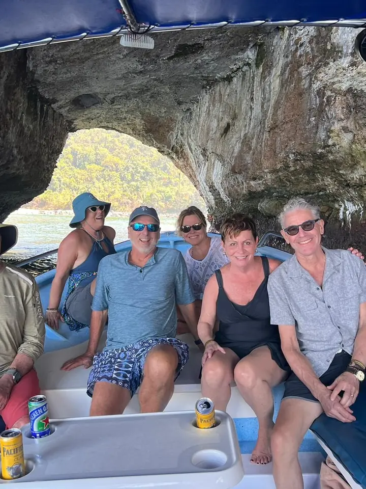 A group of friends smiling aboard one of our pangas, under a rock arch in the bay