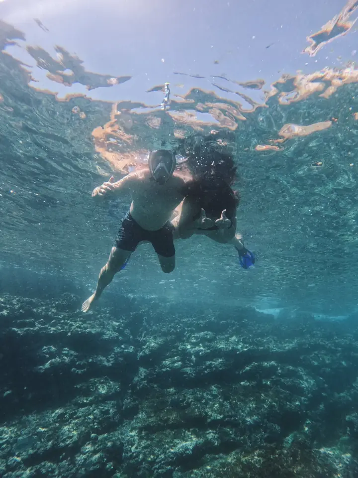Two people snorkeling in clear water over the reef